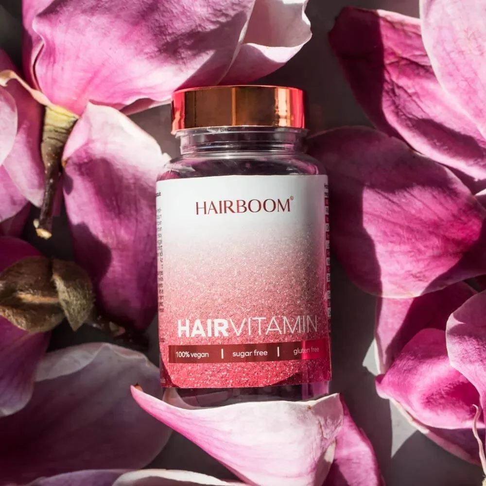 Kapsułki Hair Vitamin wśród płatków kwiatów